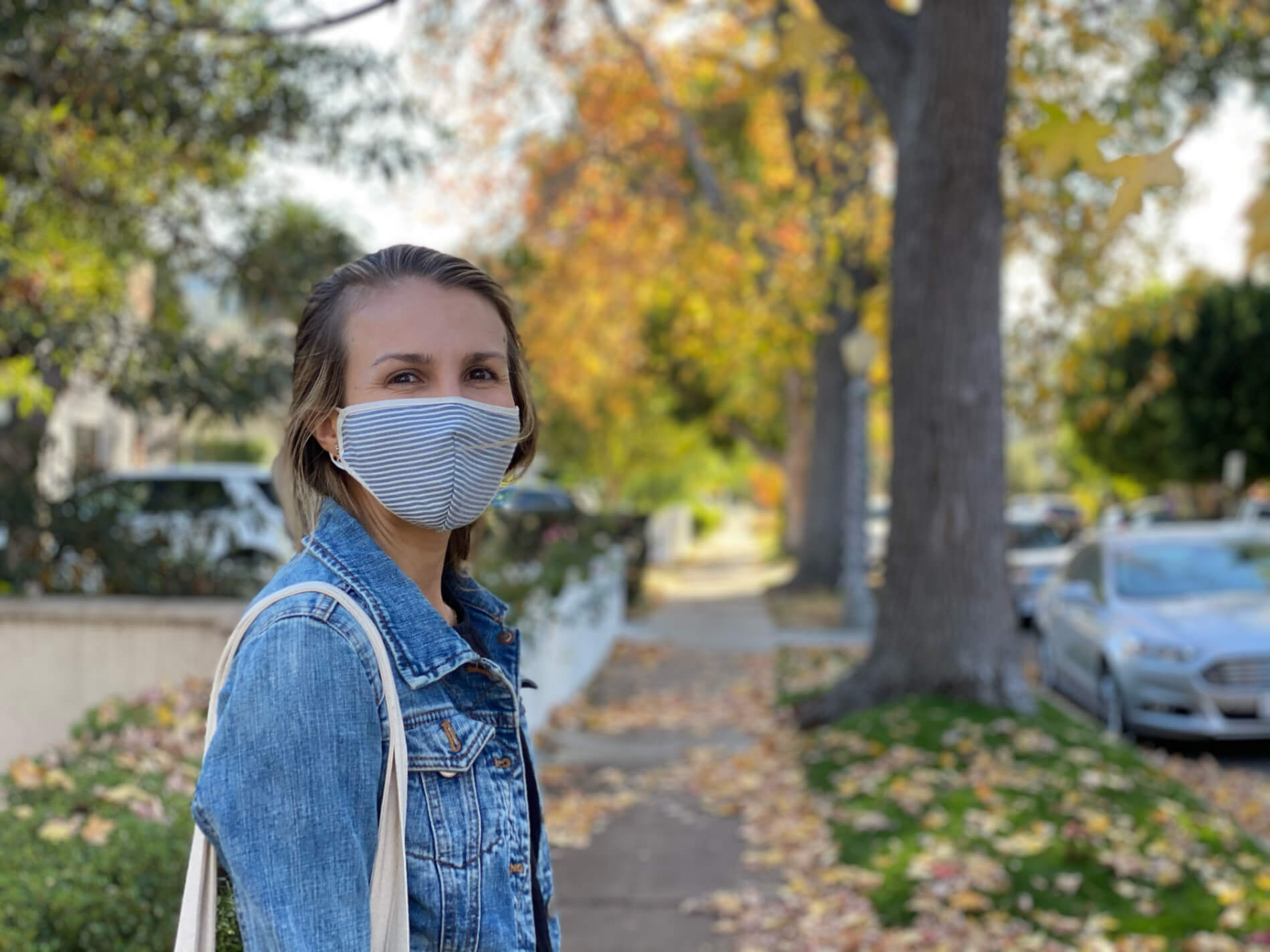 Marika Price wearing a face mask posing on a sidewalk during an autumn walk in quarantine