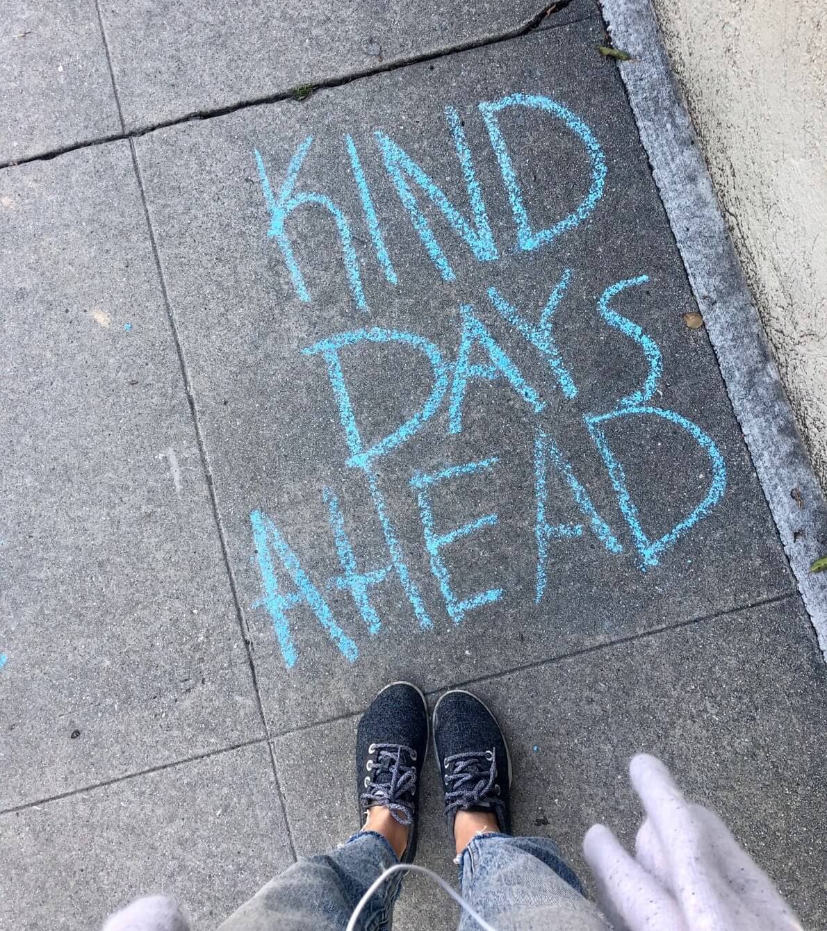 A note written on a sidewalk in chalk that says "Kind days ahead"