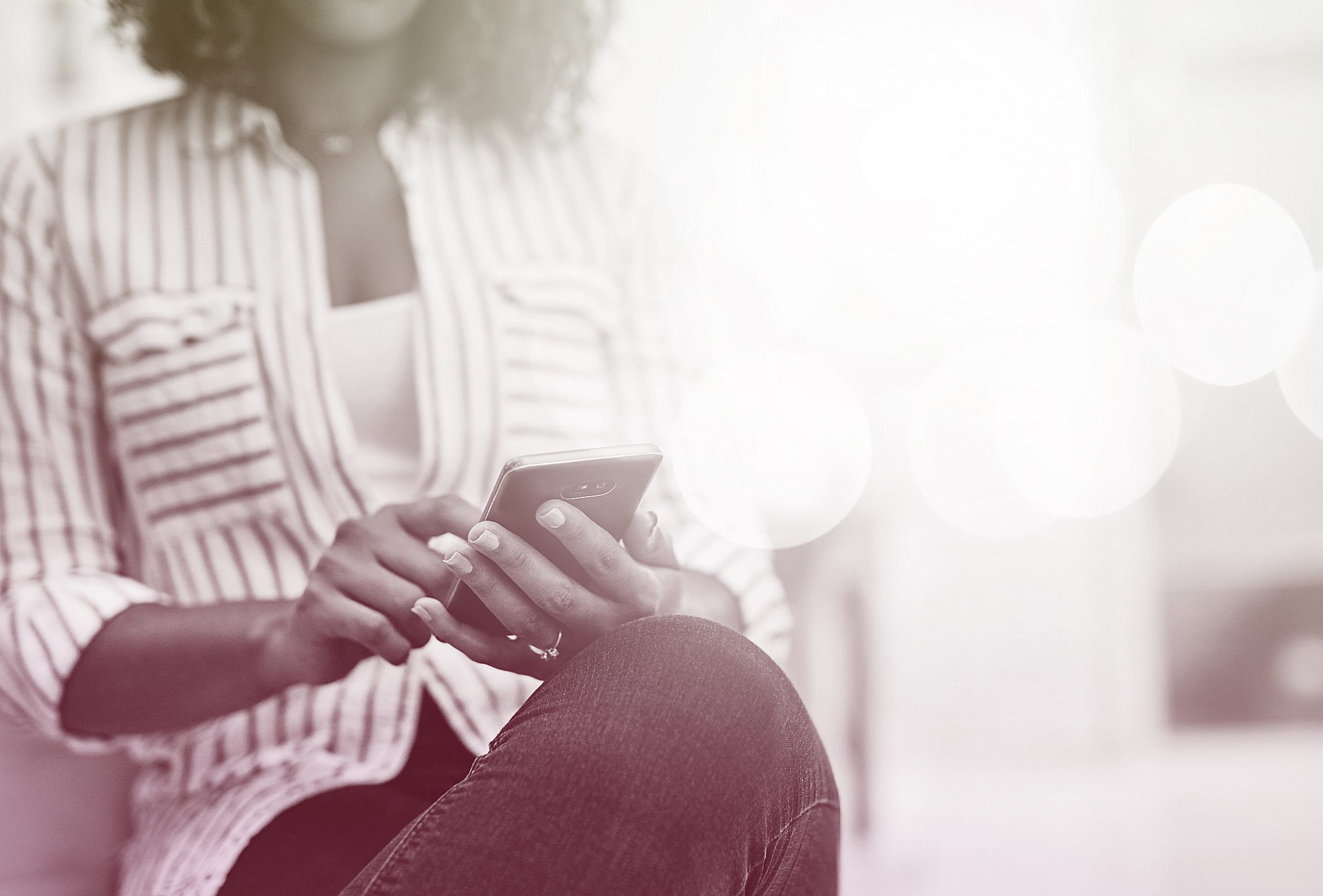 woman sitting with legs crossed while looking at cell phone