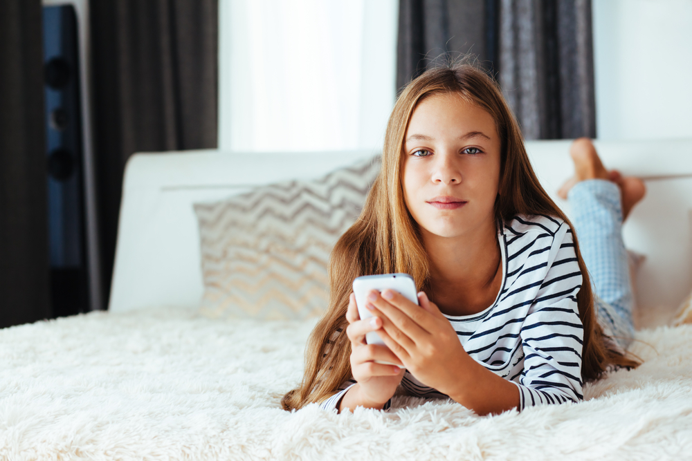 Tween Girl Texting On Bed