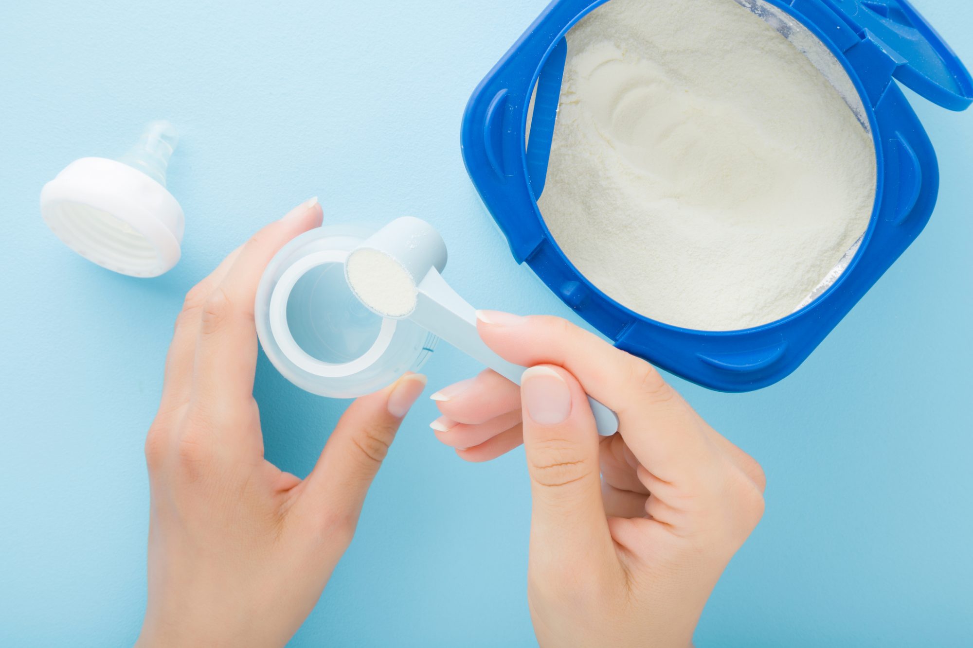 An image of a woman scooping baby formula.