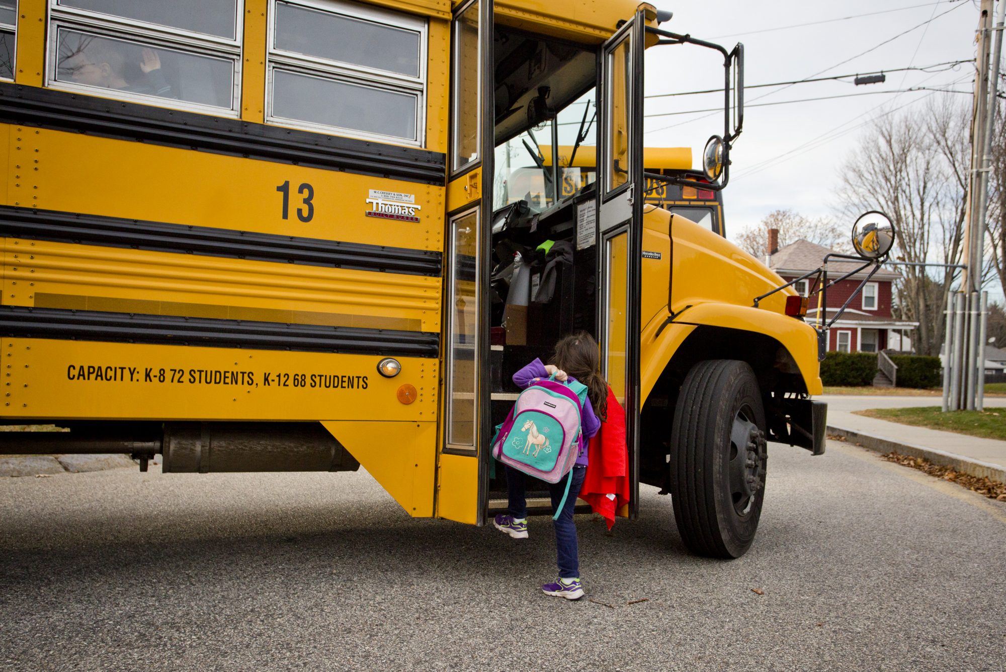 An image of a little girl getting onto a school bus.