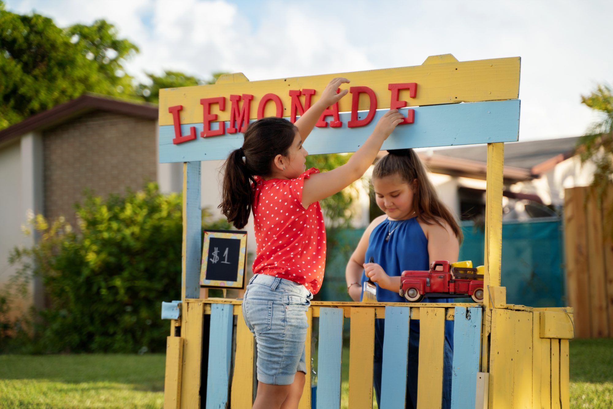 An image of two girls putting together a lemonade stand.