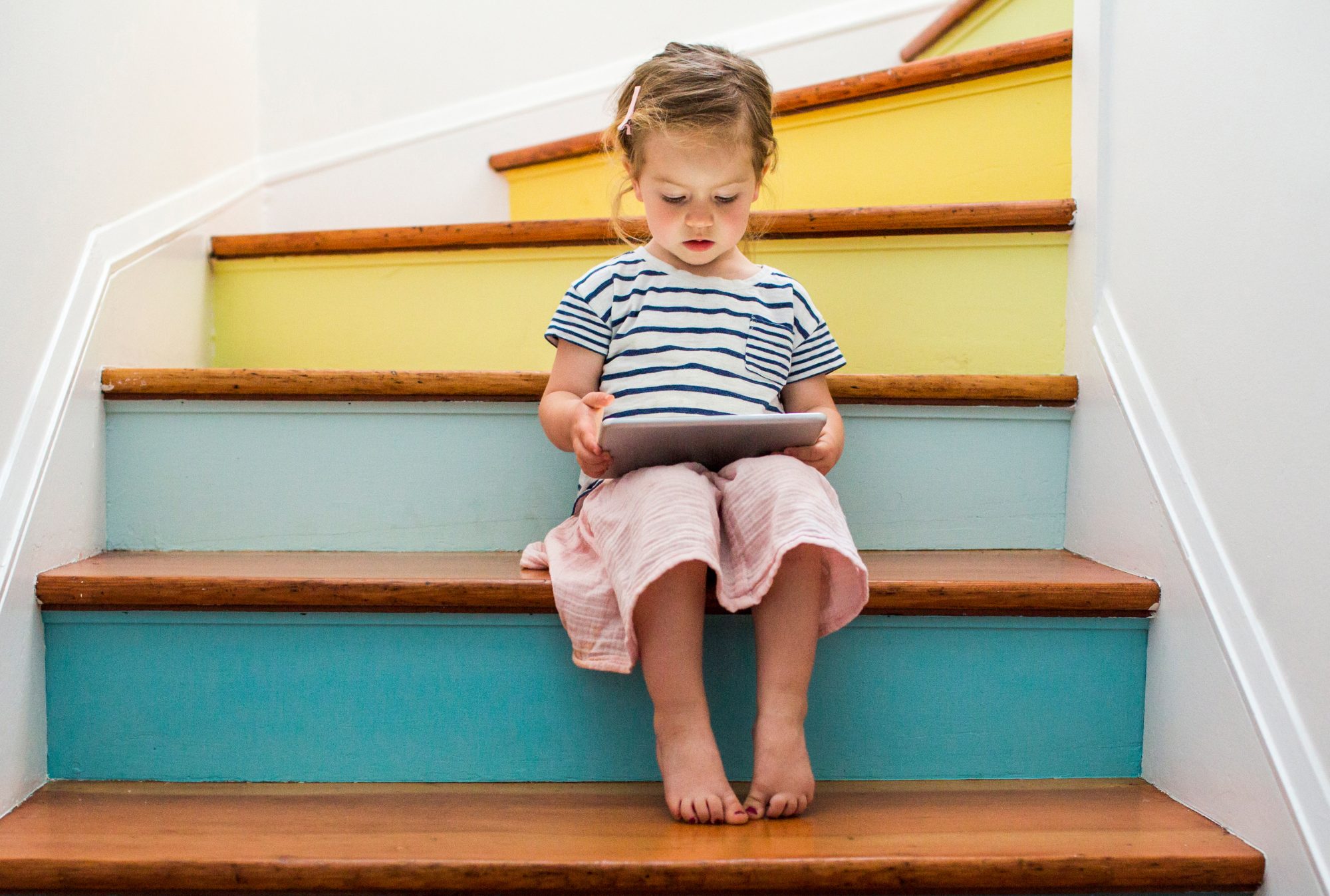 An image of a girl using her tablet on a staircase.