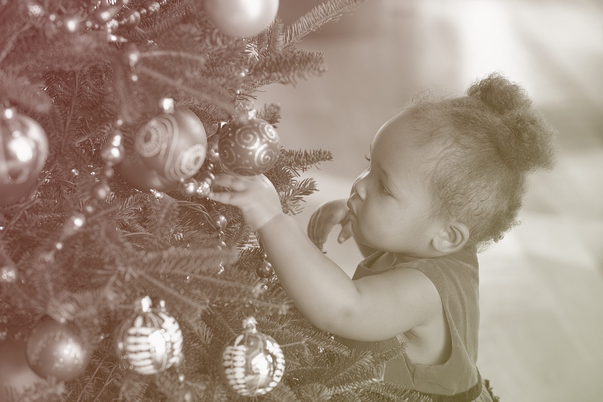 baby touching decorated Christmas tree