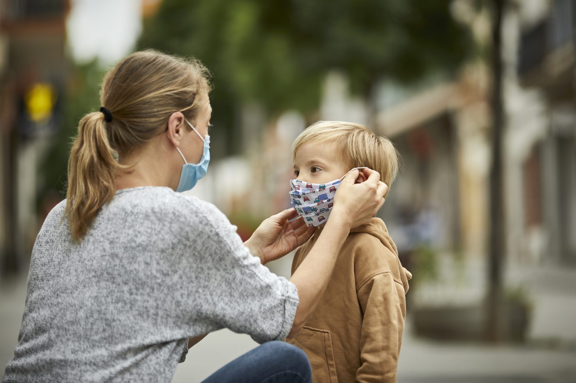 An image of a mo putting a mask on her daughter.