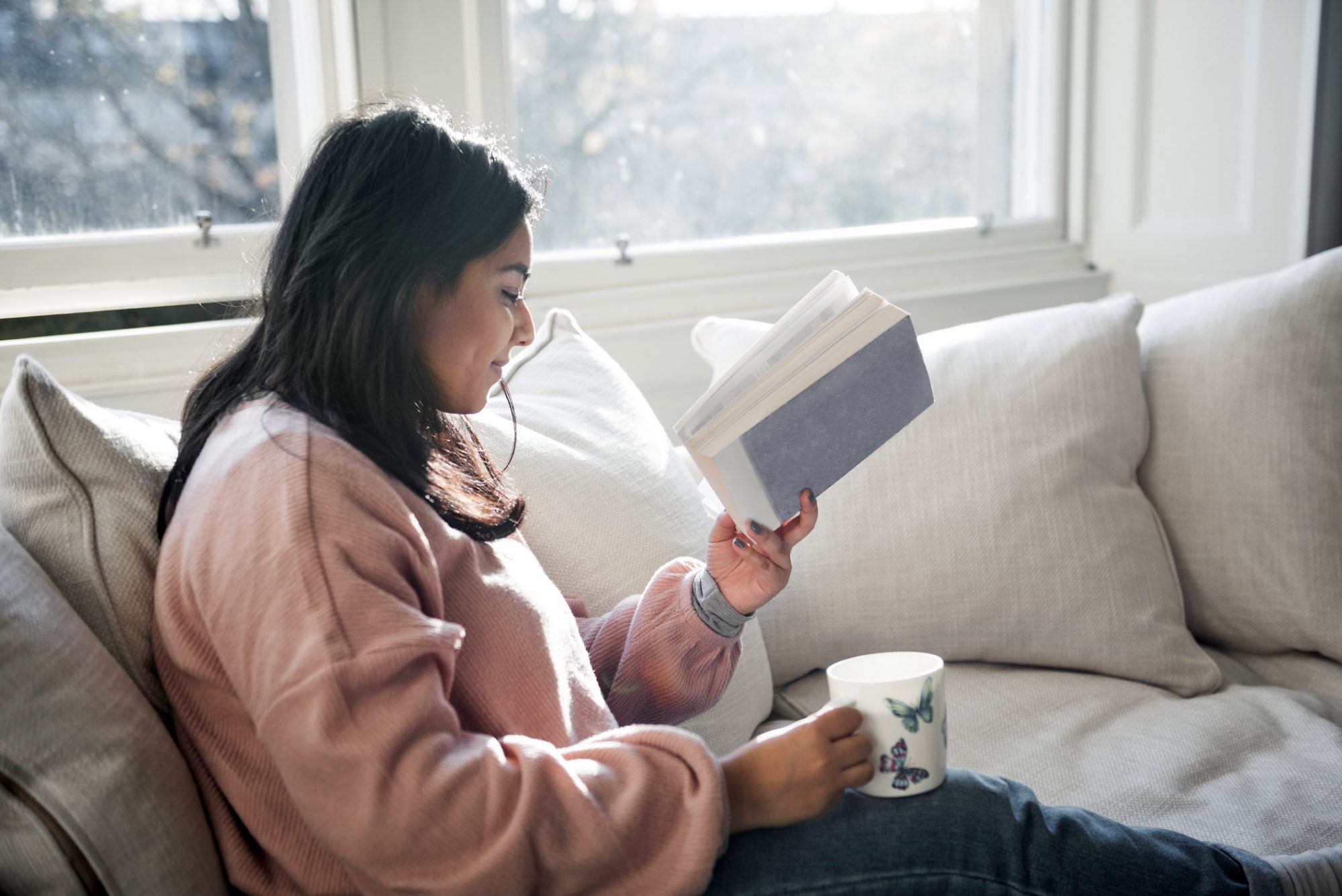 An image of a woman reading on her couch.