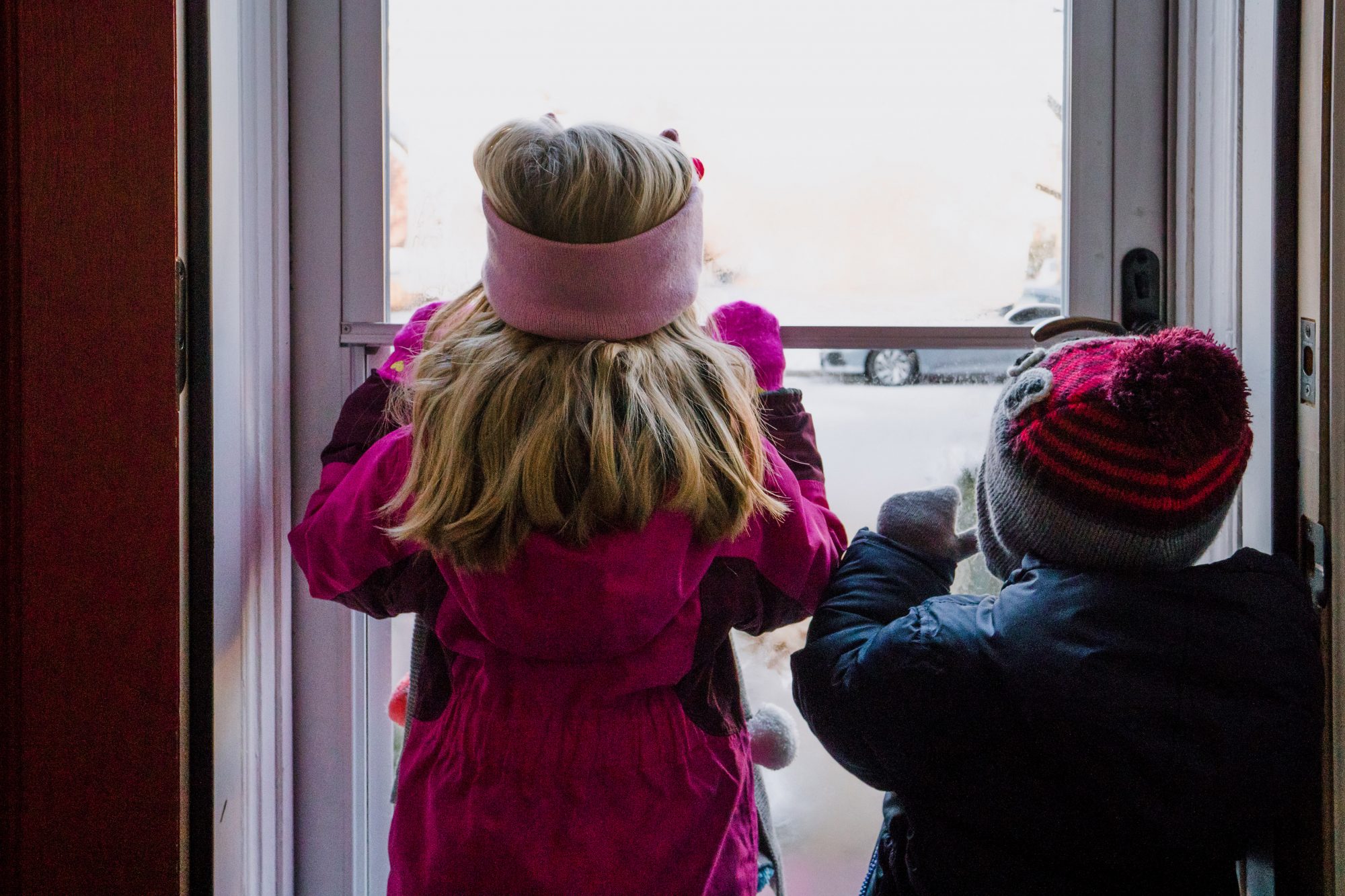 An image of children looking out a snowy window.