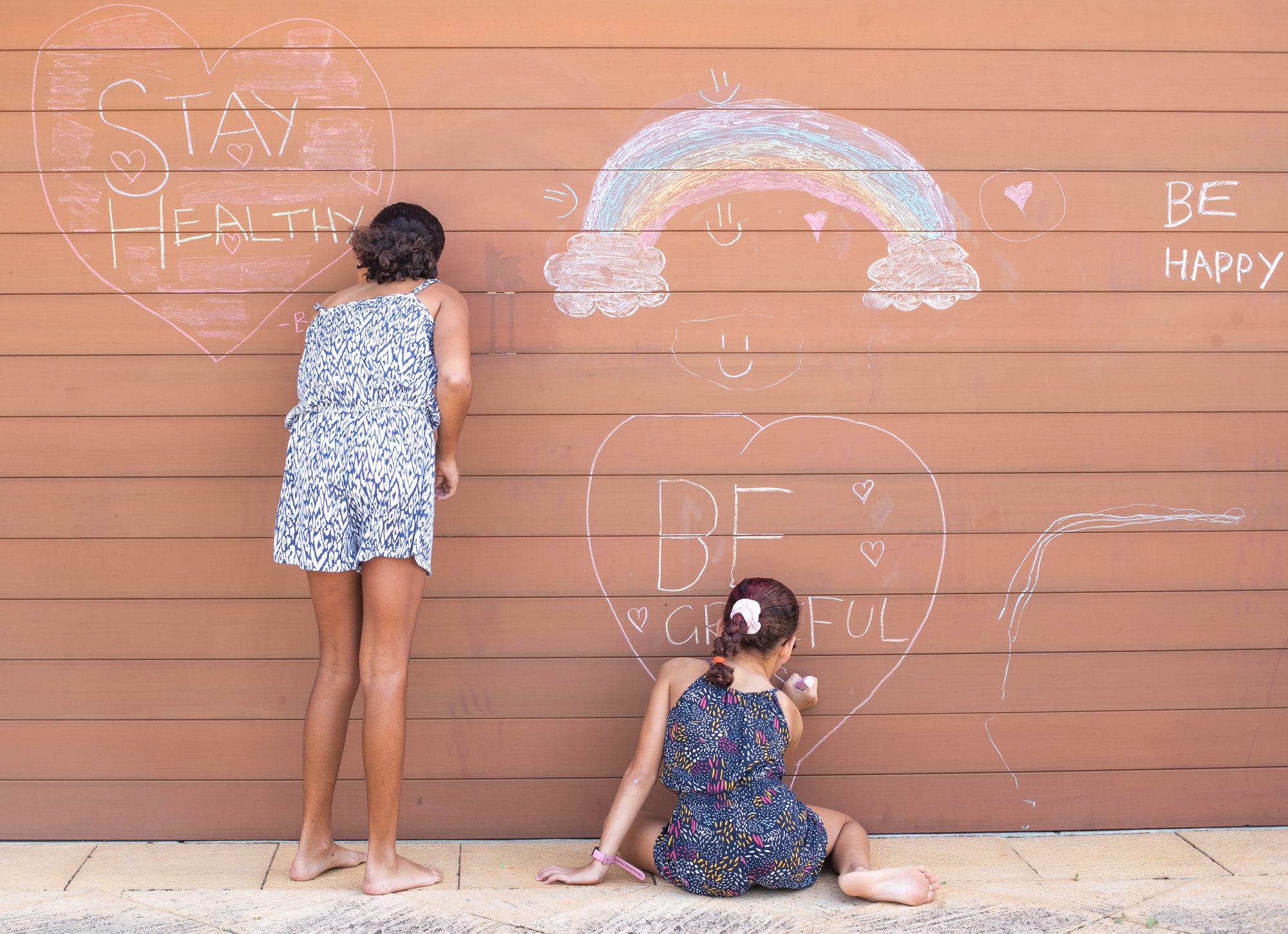 An image of two girls drawing with chalk.