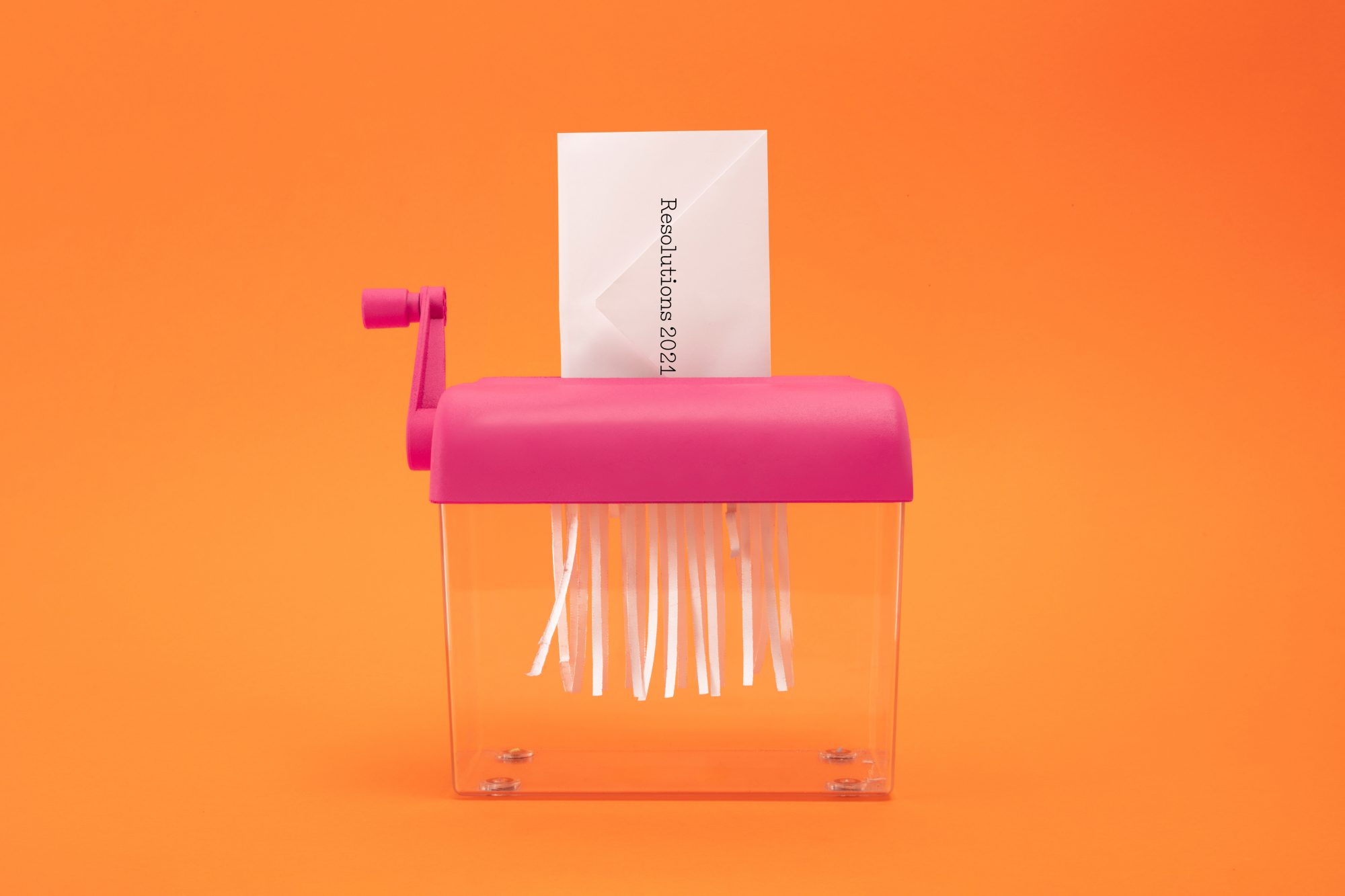 An image of a paper shredder shredding an envelope with New Year's resolutions inside.