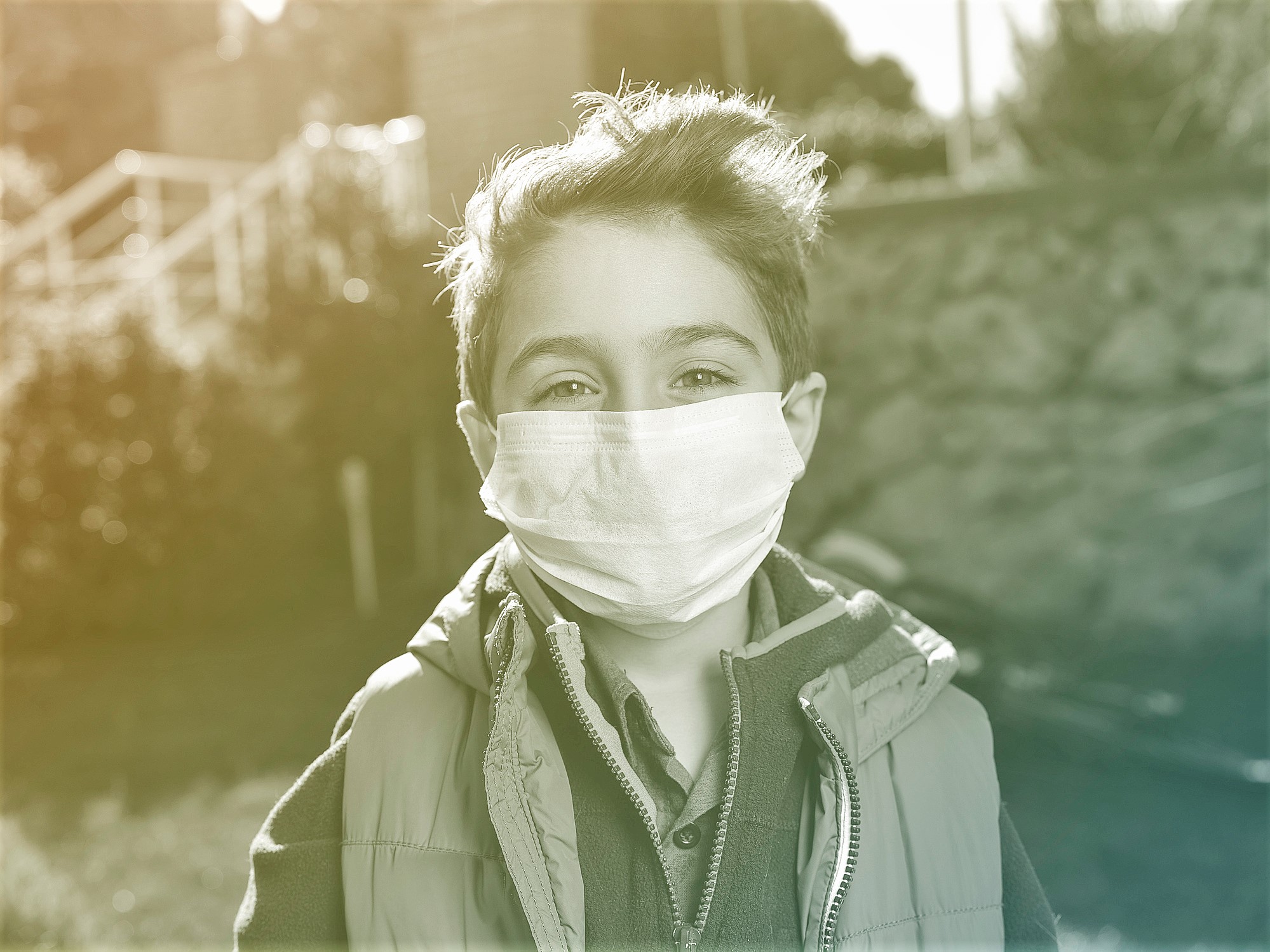 Portrait of happy boy with surgical mask standing in the garden