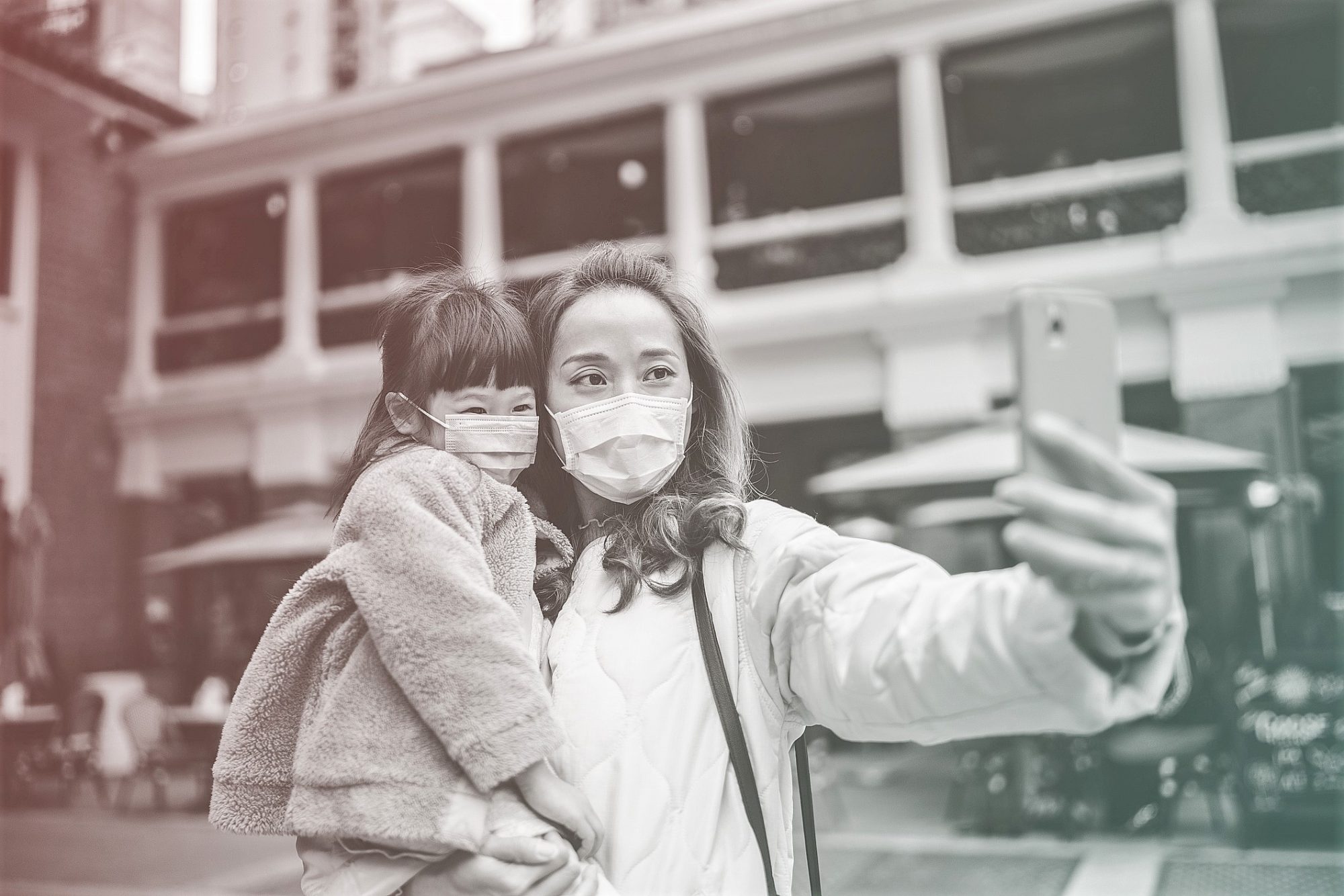 mother and daughter wearing face mask using cell phone